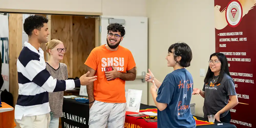Students laughing at a COBA event near recruiting tables.
