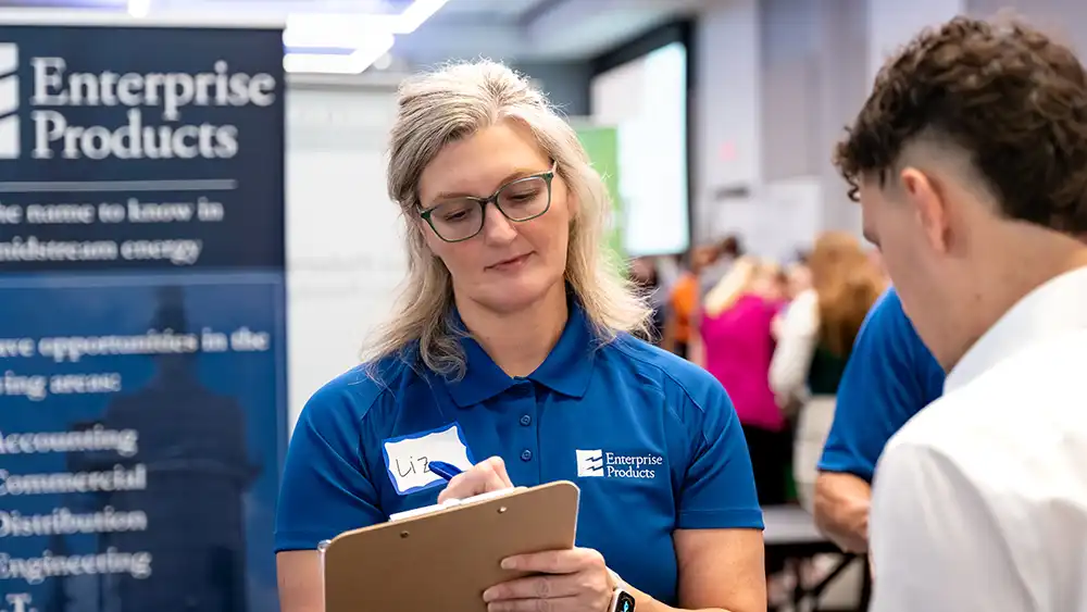 A recruiter writing down a student's information on a clipboard.