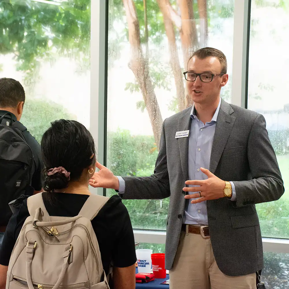 A recruiter discussing something with a student near their table.