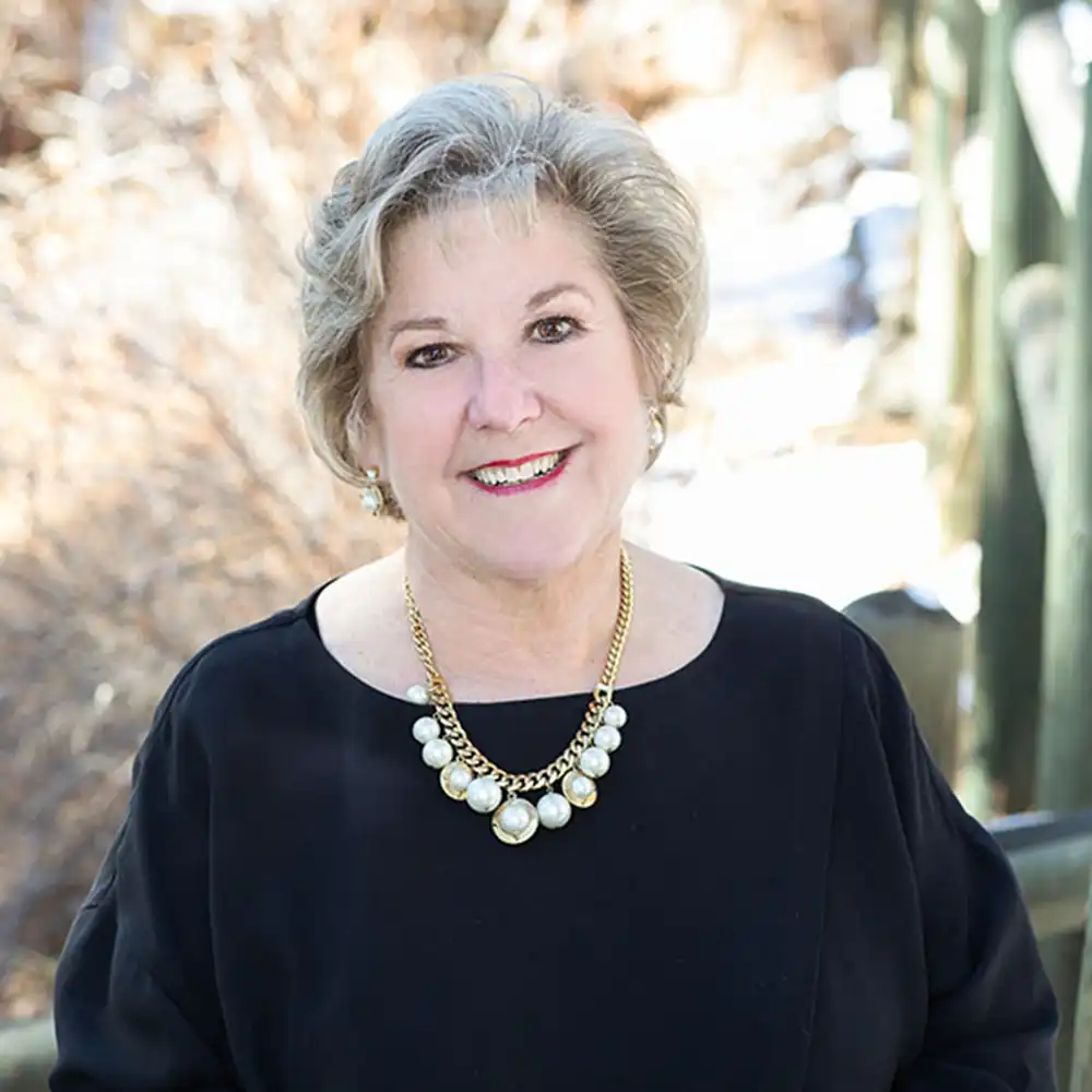 Smiling middle-aged white woman with a black top and white necklace.