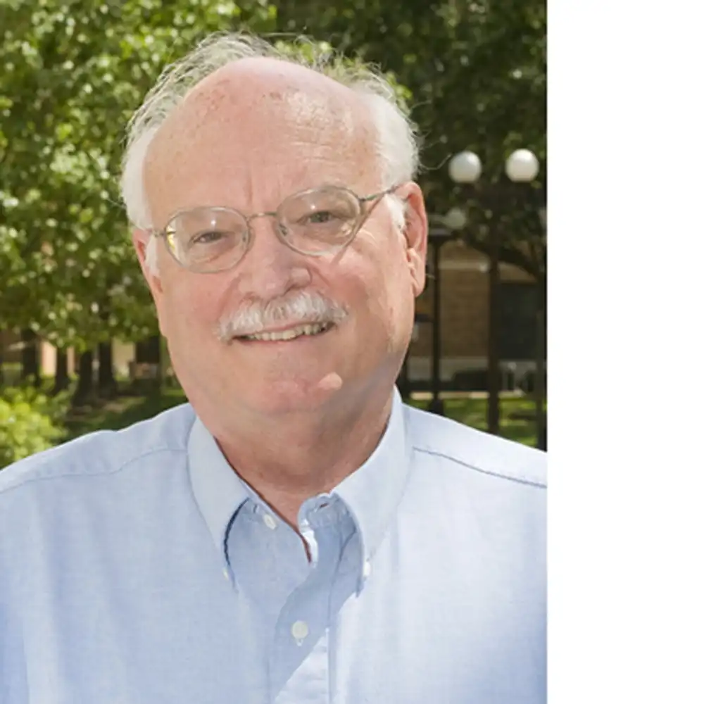 Smiling older white man in a pale blue button-up shirt.