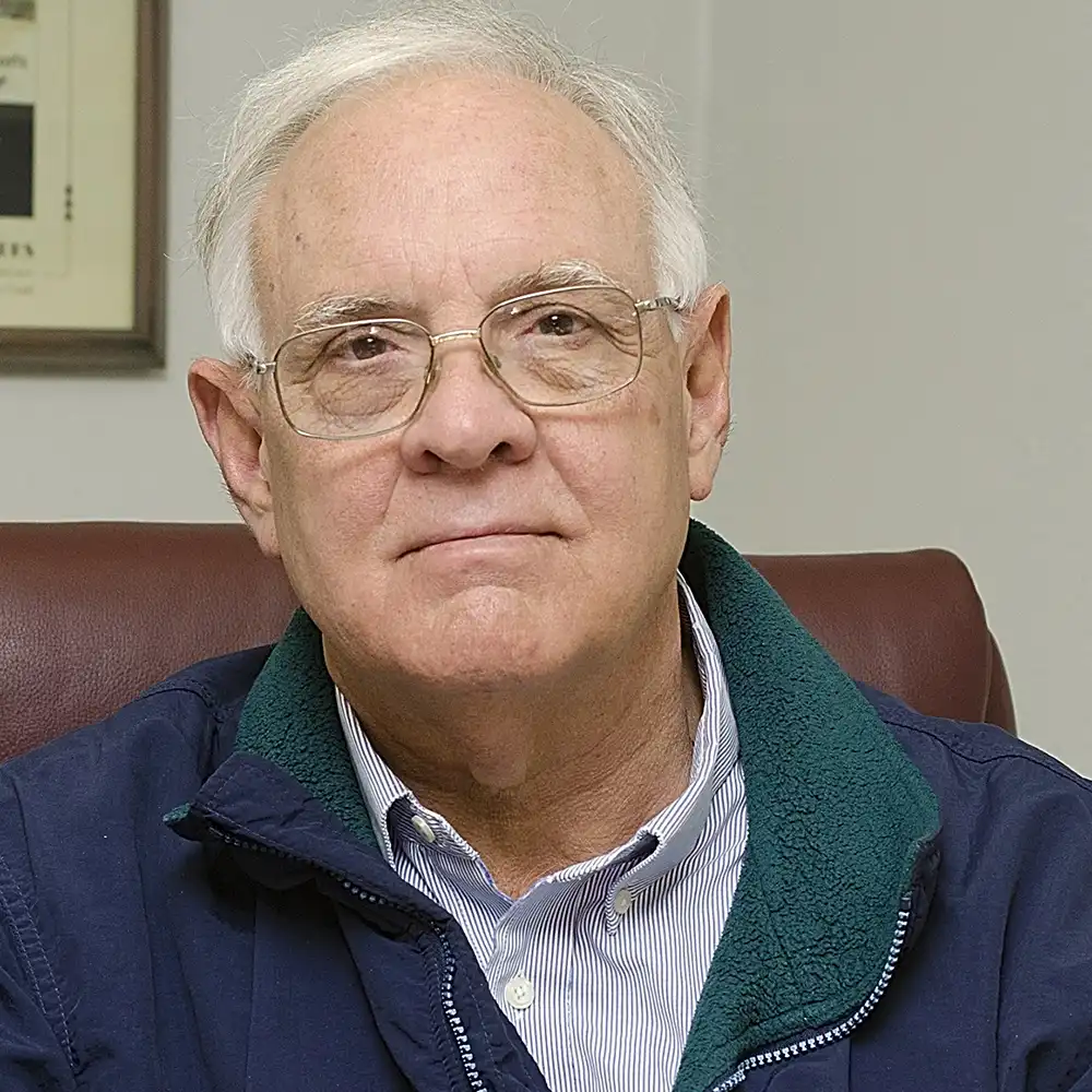 Older white man in glasses and a zip-up sweater.