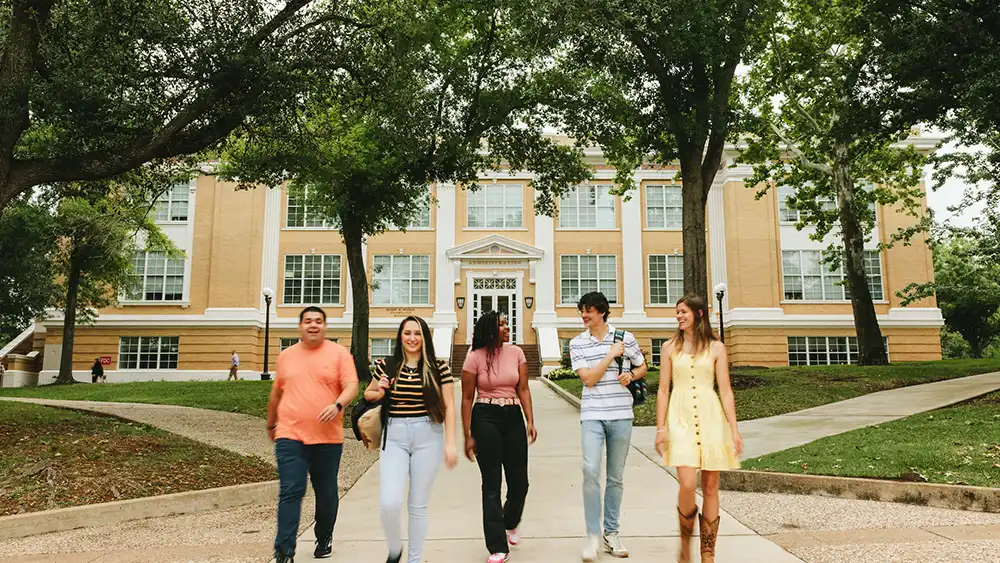 Five student walking in from of the administration building.