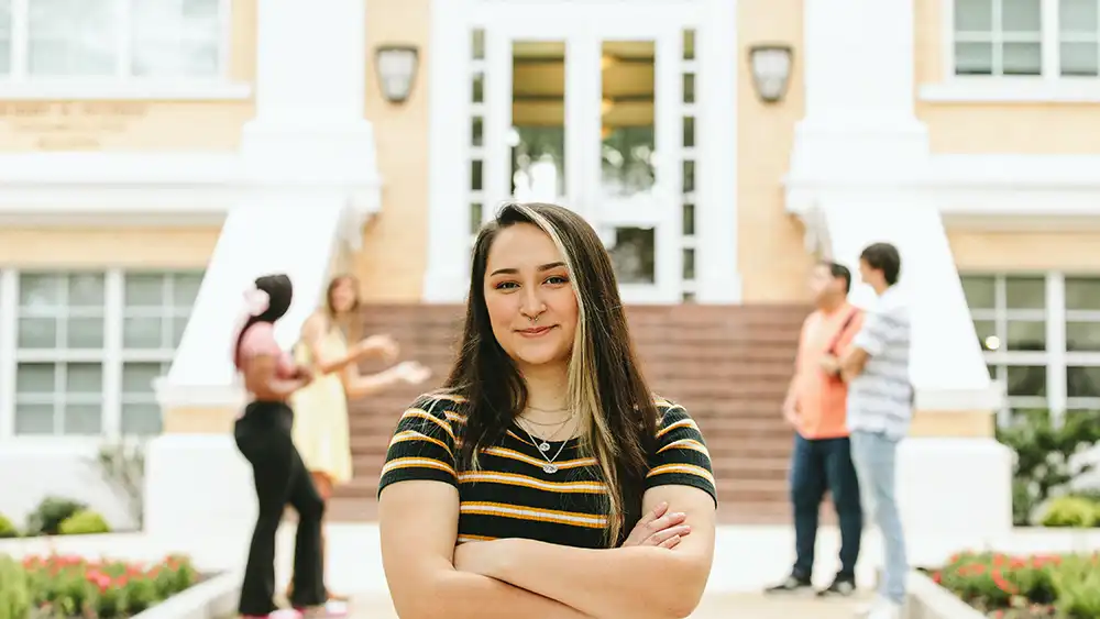SHSU student poses for a picture while their classmates engage in conversation.