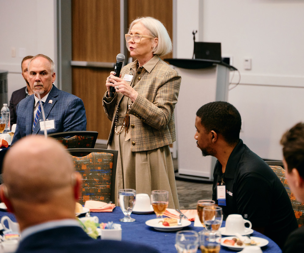 Professor speaking to the camera in a classroom style class, with her hands opened.