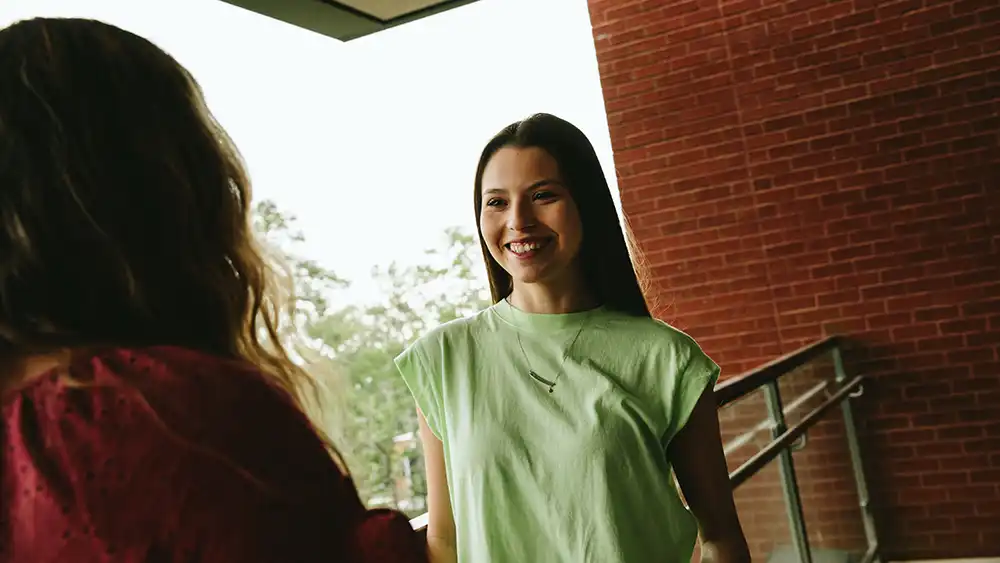 A student meeting a faculty member in between classes.