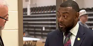 Professor speaking to the camera in a classroom style class, with her hands opened.