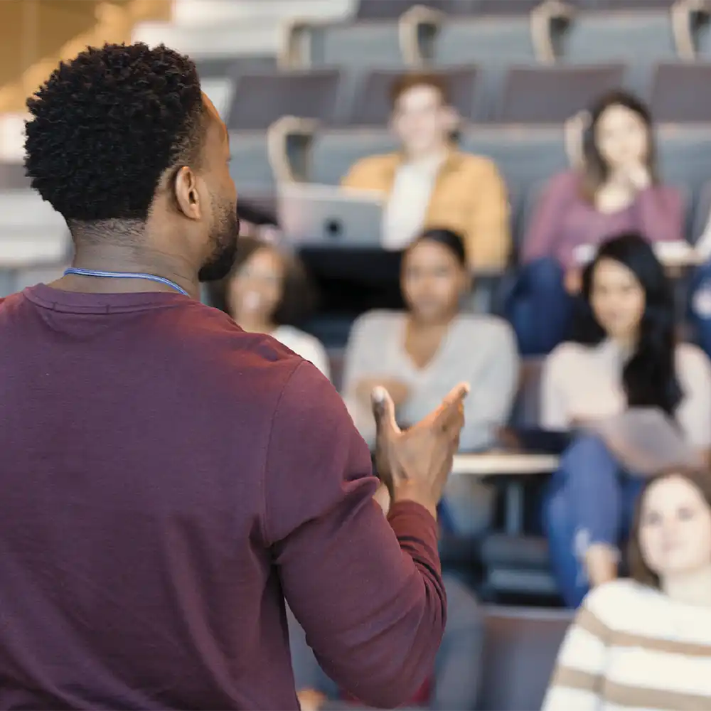 Two women looking at each other, smiling, sitting down, working on an assignment.