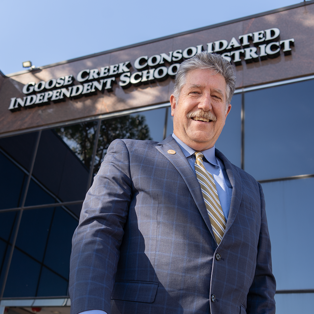 Two women looking at each other, smiling, sitting down, working on an assignment.