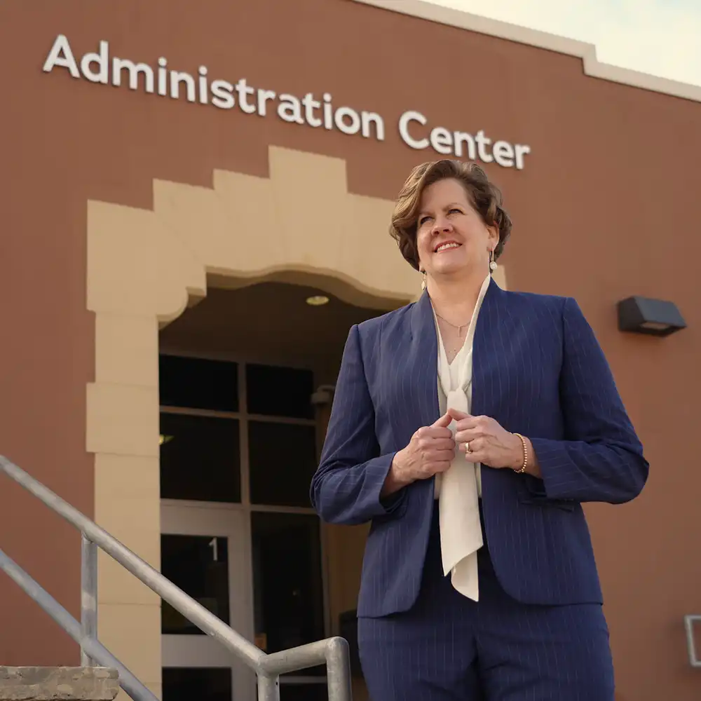 Woman smiling, posing, in front of a school