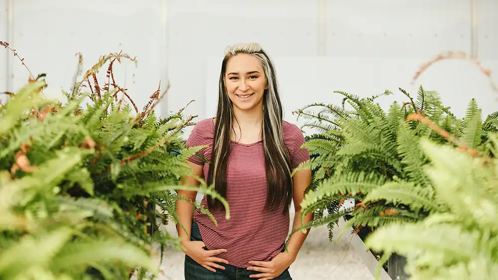Student standing in greenhouse
