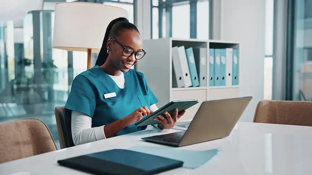 Two women looking at each other, smiling, sitting down, working on an assignment.