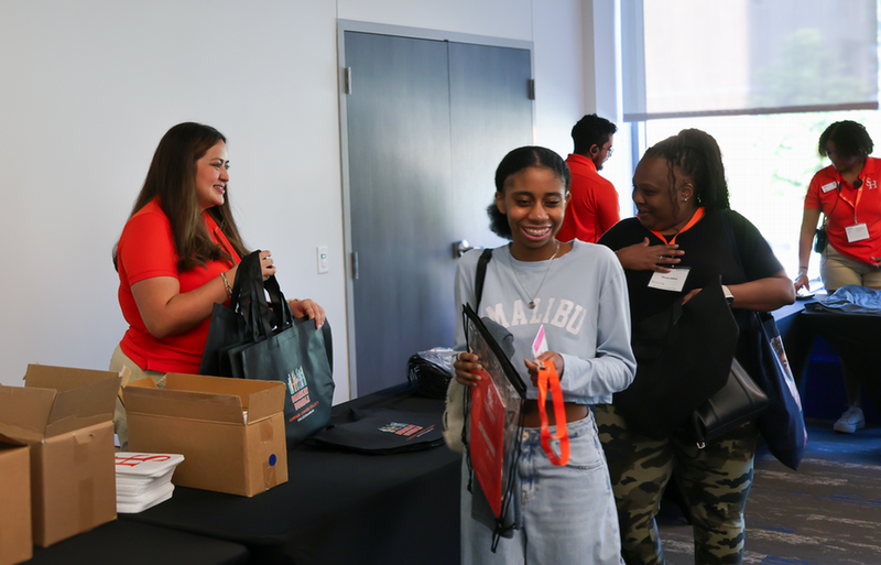 Alyssa Rodriguez hands out tote bags at New Student Orientation.