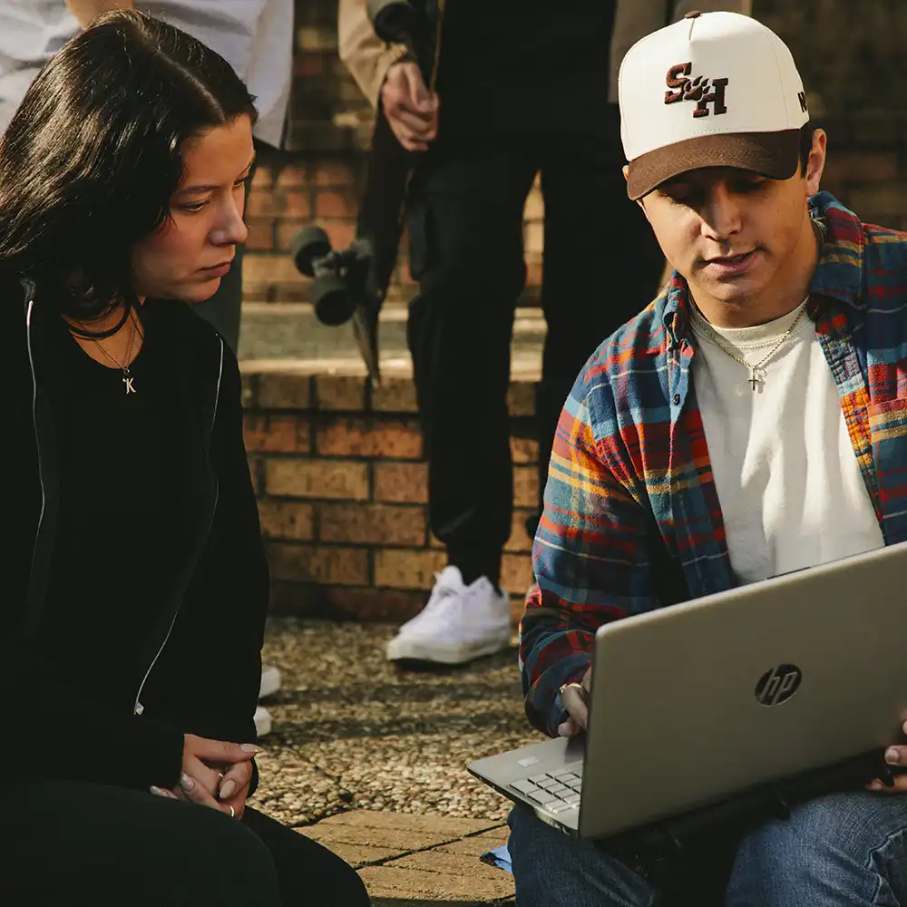 A student showing another student something on their laptop.