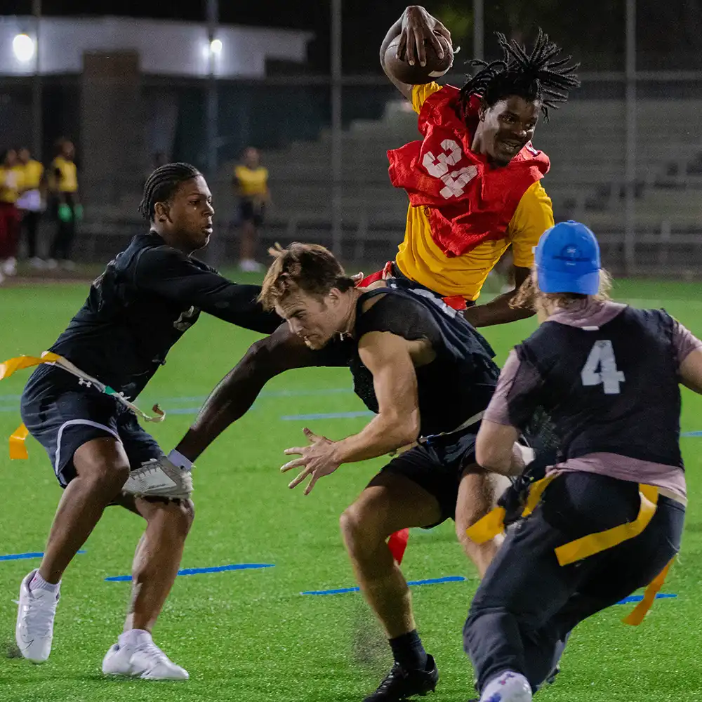College boys playing flag football at night.