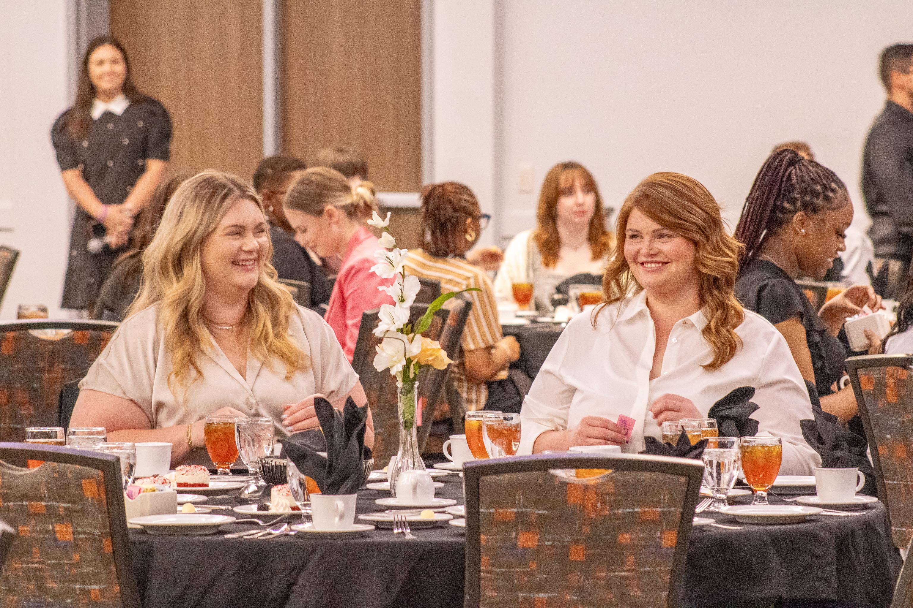 Two SHSU students smiling at an etiquette dinner inside the Orange Ballroom.