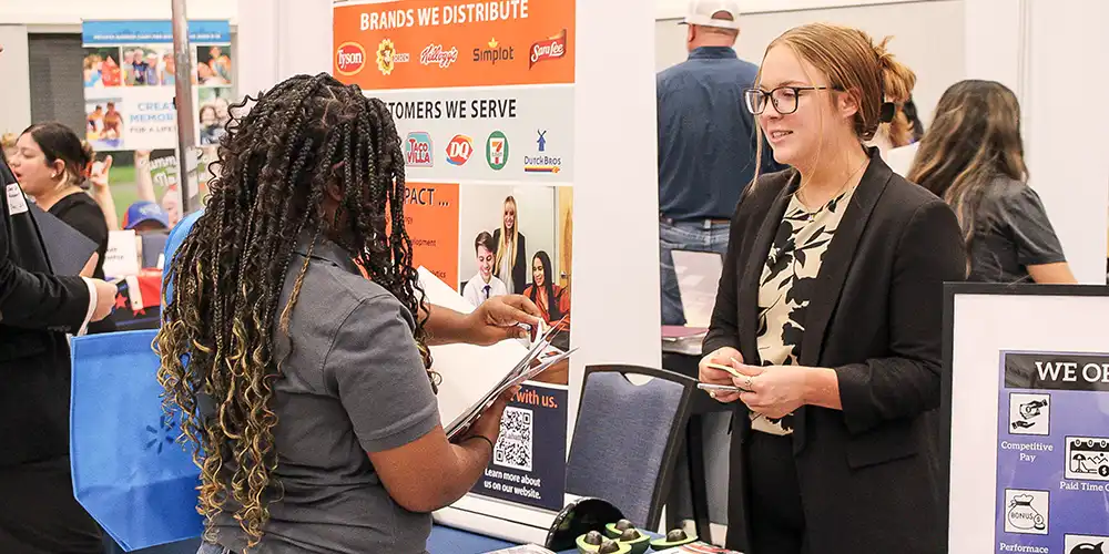 A student handing a resume to a recruiter during an SHSU Career & Internship Fair.
