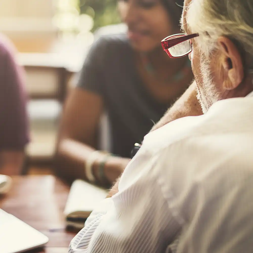 Three people having a discussion around a laptop