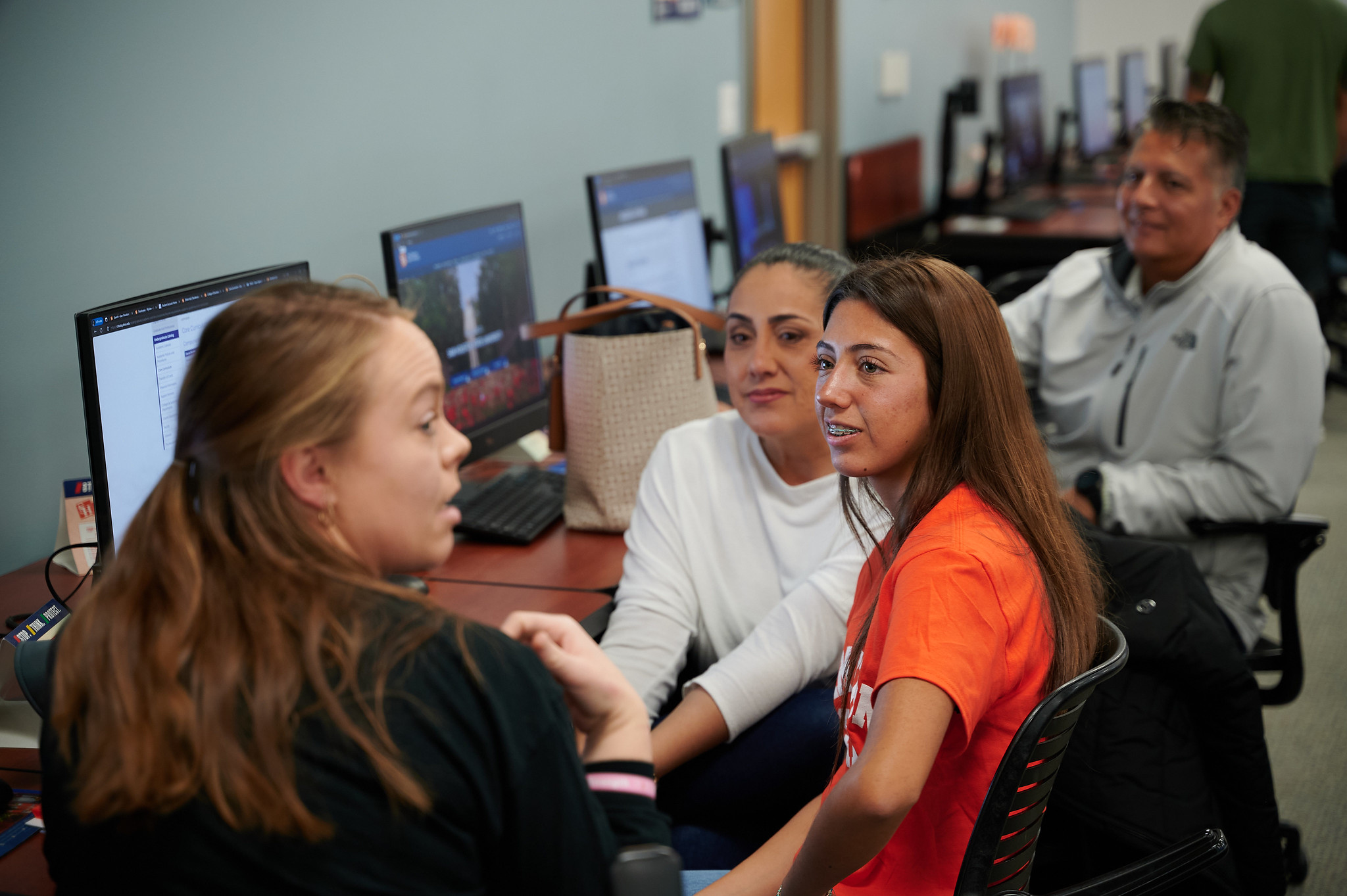 SHSU staff member talking to an SHSU student and their family in front of the computer.
