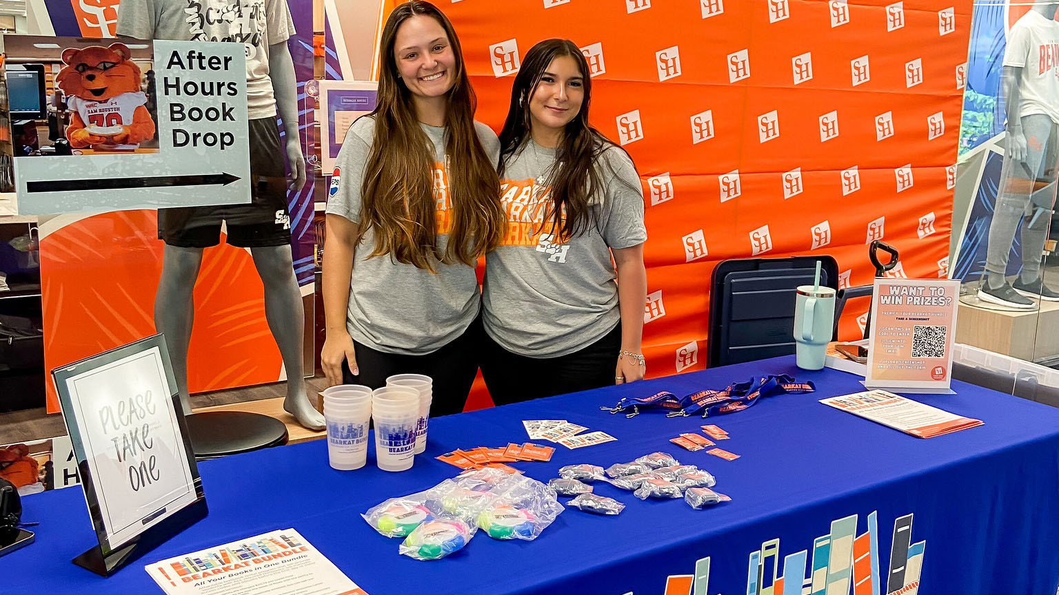 Two staff members standing at their table with information about books at SHSU.