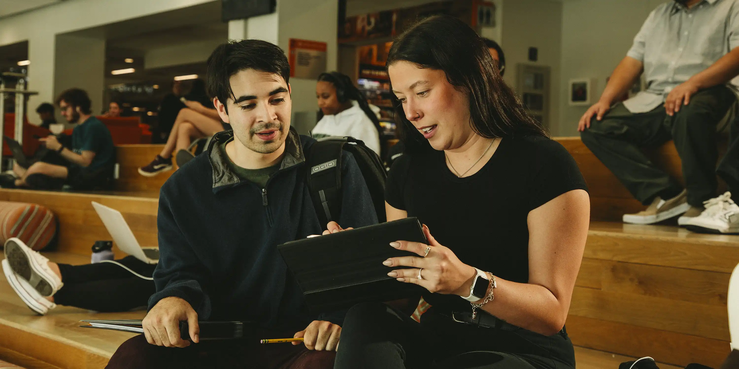 Two students sitting together looking at a laptop