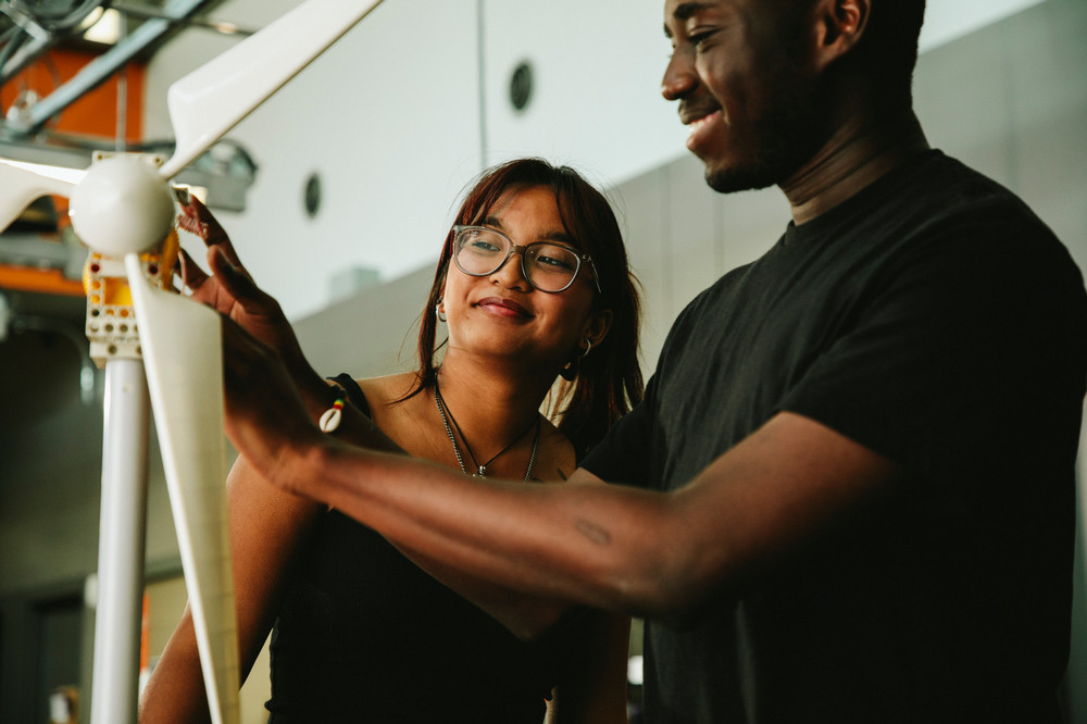    ​​Two smiling students are engaged in working on an engineering project.​ 
