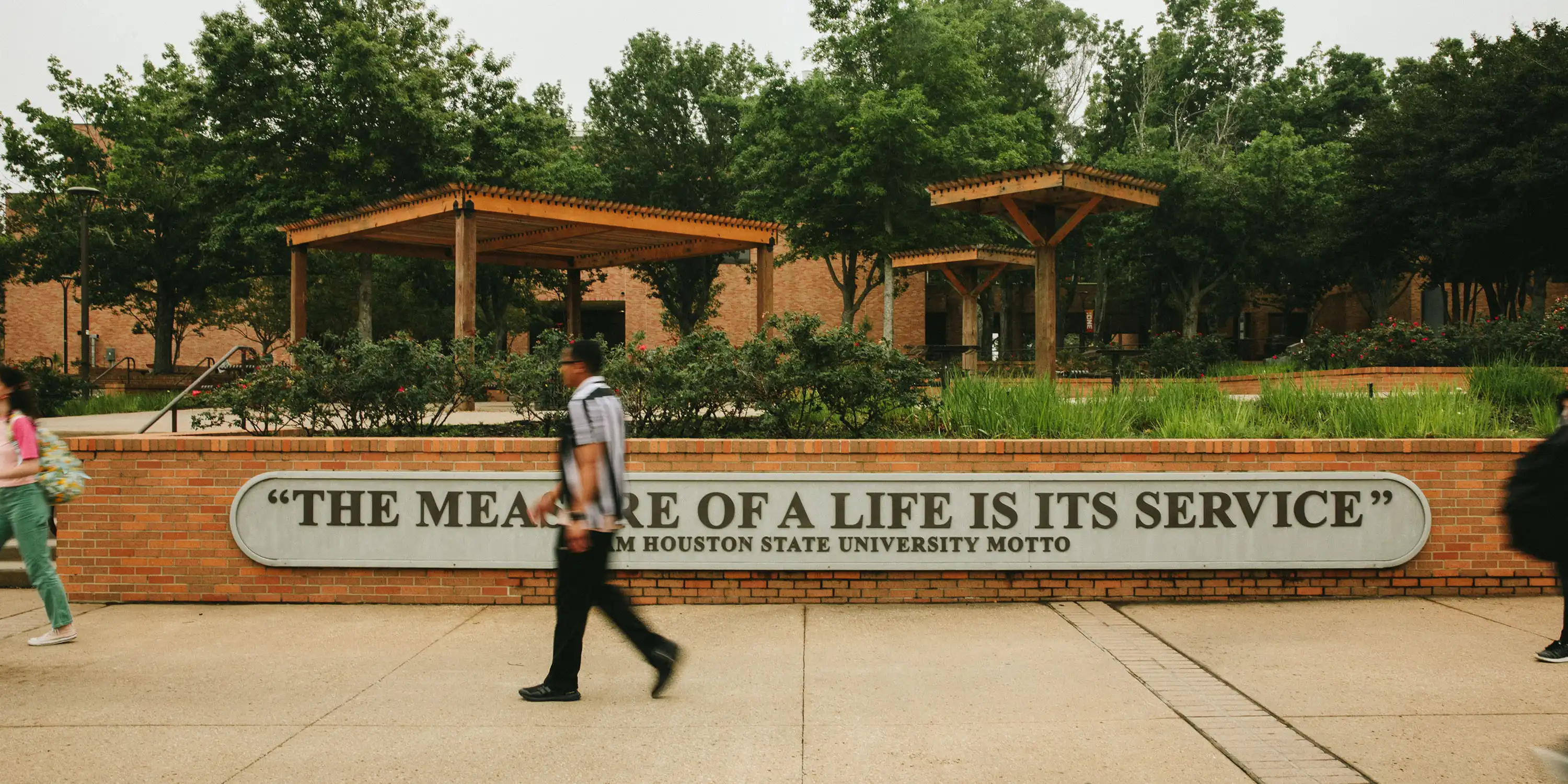 Students walking by SHSU motto